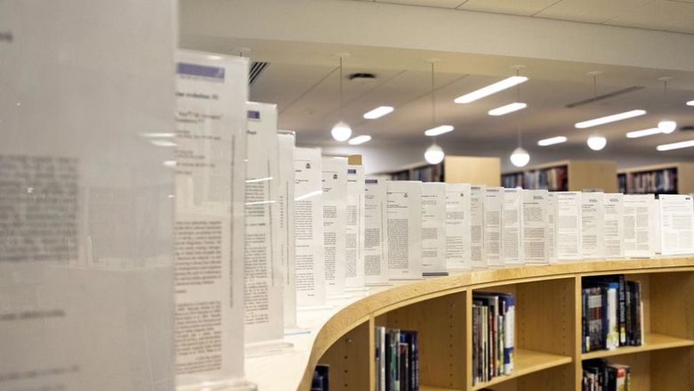 framed copies of faculty members' published works line the top of a display area in the Scranton campus library