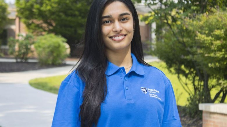 Student smiling wearing a shirt that says 'New Student Orientation' on it