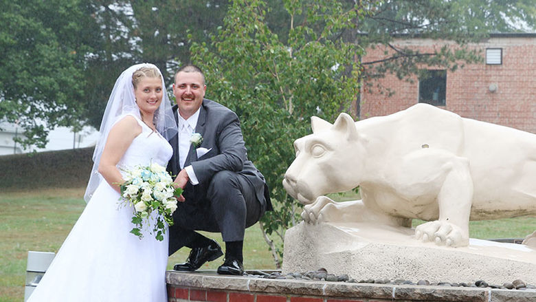 bride and groom pose near Nittany Lion statue