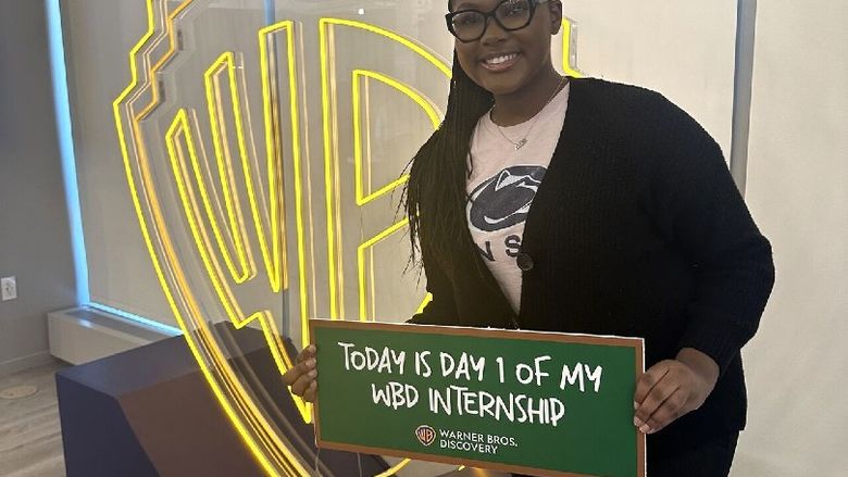 A student holds a sign that reads Today is Day 1 of my WBD internship