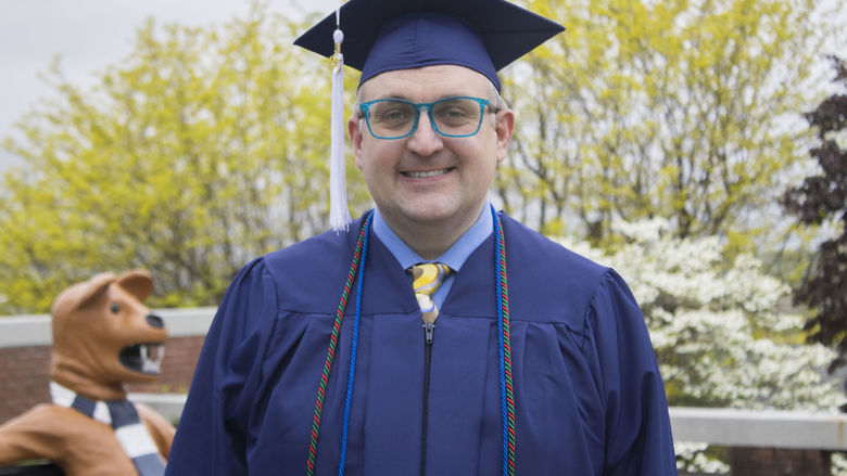 Student wearing commencement regalia and smiling