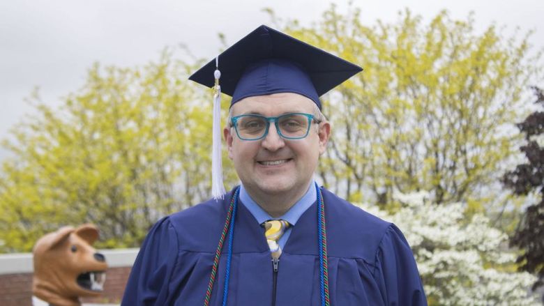 Student wearing commencement regalia and smiling