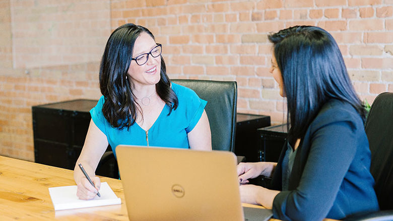 two women review laptop and discuss professional development 