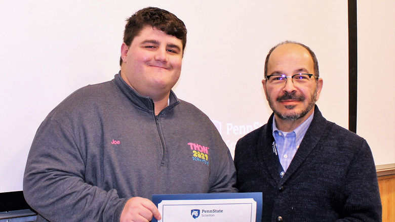 smiling chancellor presents smiling student with certificate