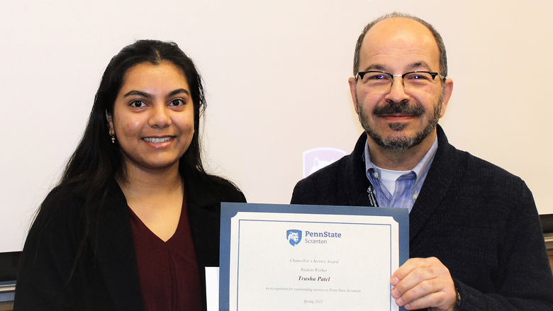 smiling chancellor presents smiling student with certificate