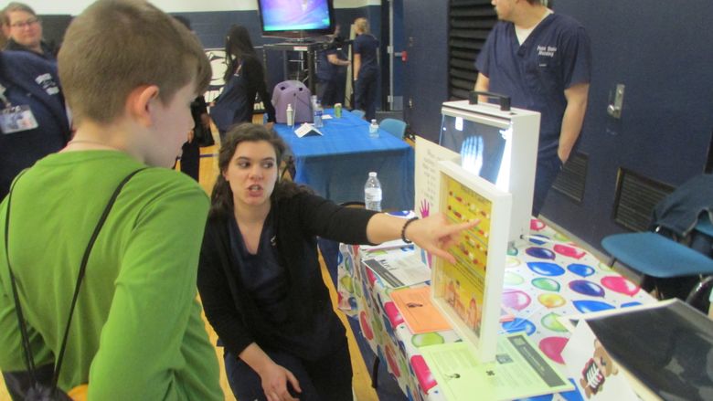 nursing student talking to child at info table