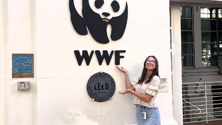 A student stands next to a World Wildlife Fund logo