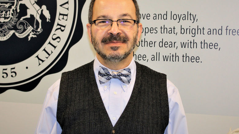 Dr. Wafa standing in front of wall with PSU alma mater graphic displayed on it