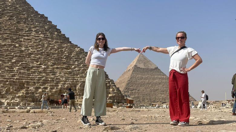 two girls pose in front of pyramids