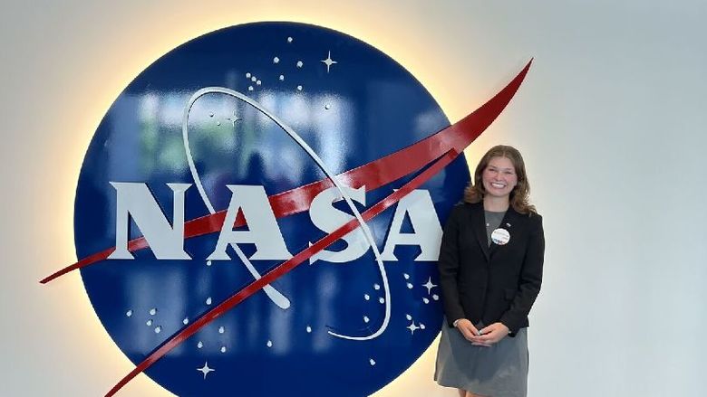 A student stands next to a NASA sign
