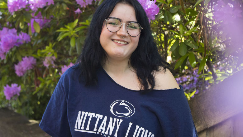 Student smiles in front of flowers