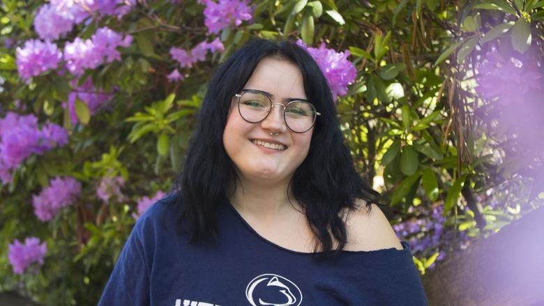 Student smiles in front of flowers