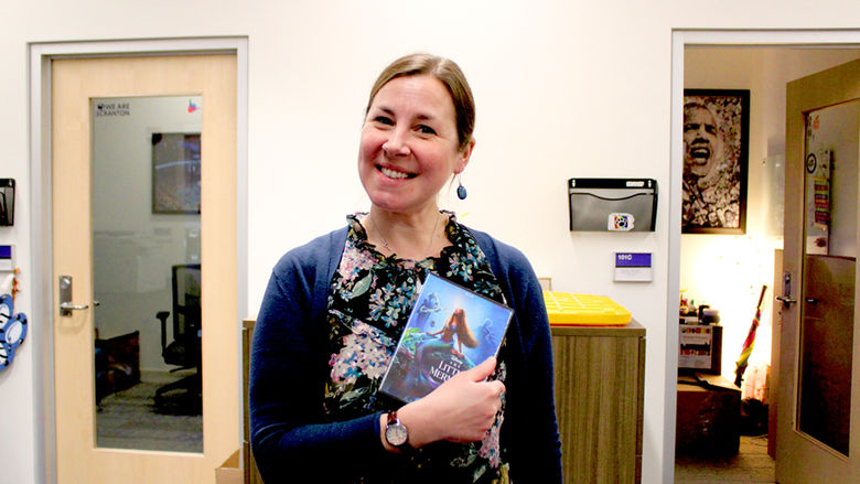 Diversity, Equity and Inclusion Coordinator Emily Glodzik shows off her borrowed DVD, "The Little Mermaid."
