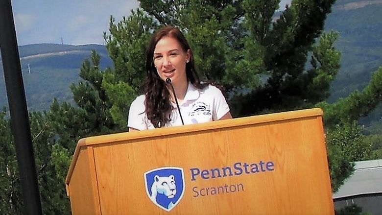 emily scarfo at a podium speaking at a campus event