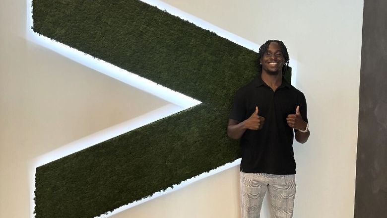 A student gives thumbs up while standing next to an Accenture logo