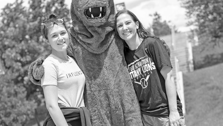 nittany lion  mascot has arms around two students