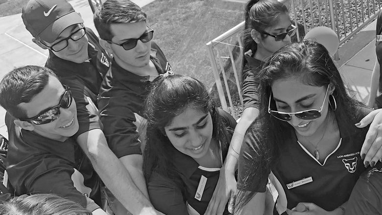 diverse group of students stack hands on hands to show unity