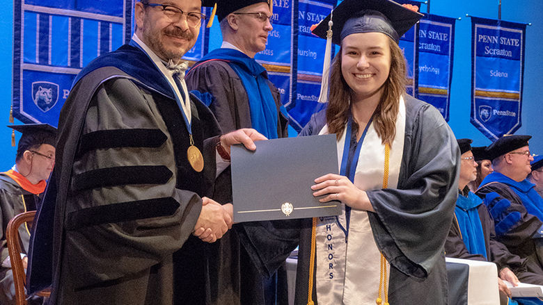Honors student, Emma Pizzolanti, receiving her diploma from Dr. Marwan Wafa on stage during 2019 commencement.