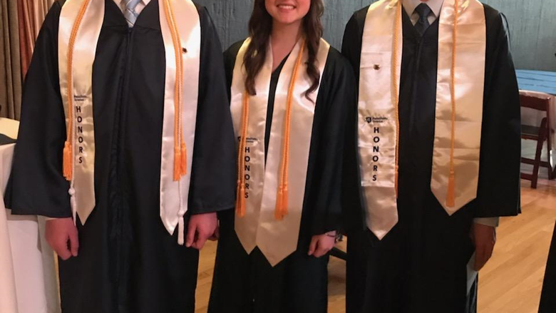 3 Honors students, Kyle Franceski, Cheyenne Tussel, and Nicholas Kremp at Commencement 2019 in their white sashes and gold cords.