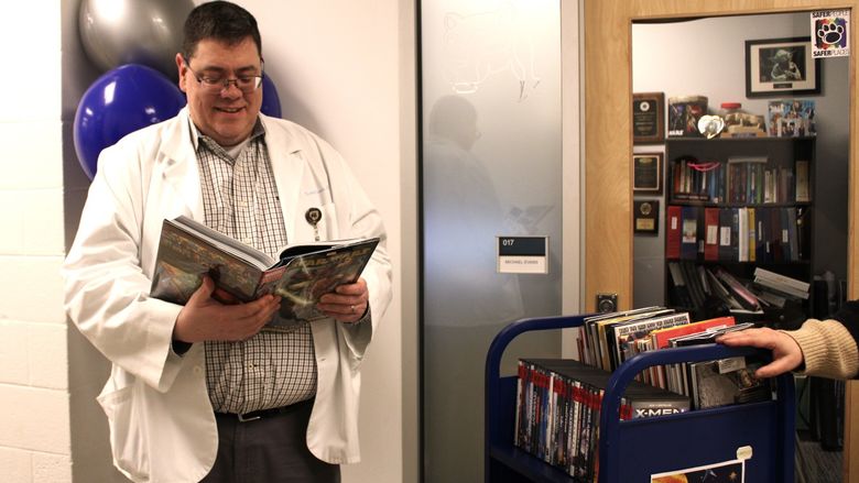 Nursing professor Mike Evans looks over a book on the Sci-Fi library cart