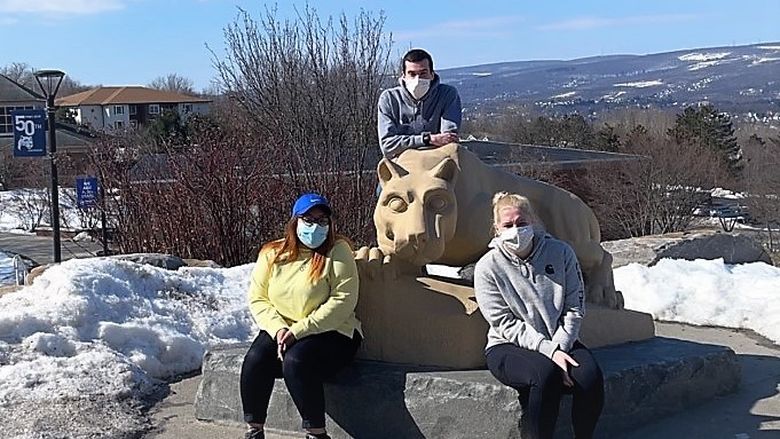 Three campus lion ambassadors pose for a photo at the Nittany Lion Shrine