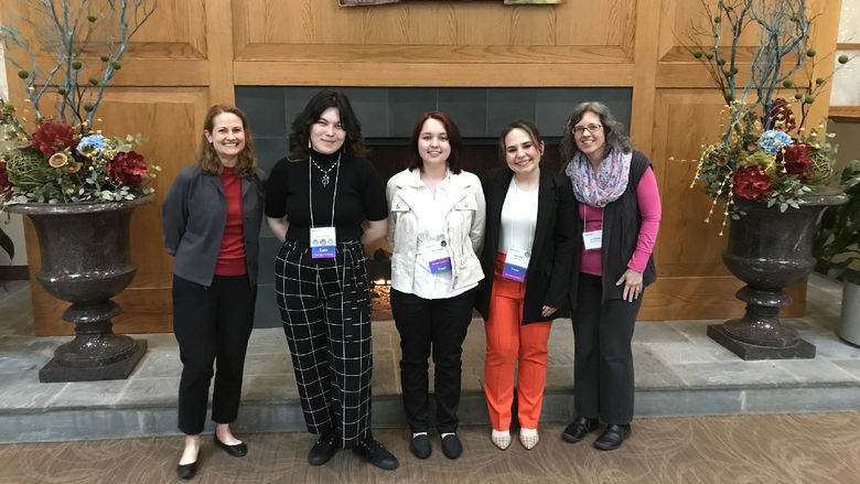 Students and chaperones pose for a photo togehter in front of a fireplace 