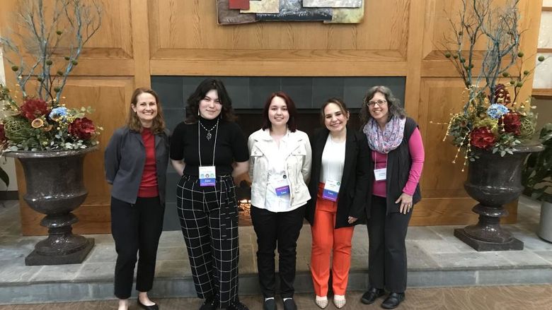 Students and chaperones pose for a photo togehter in front of a fireplace 
