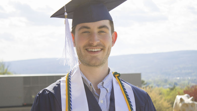 Student wearing commencement regalia and smiling