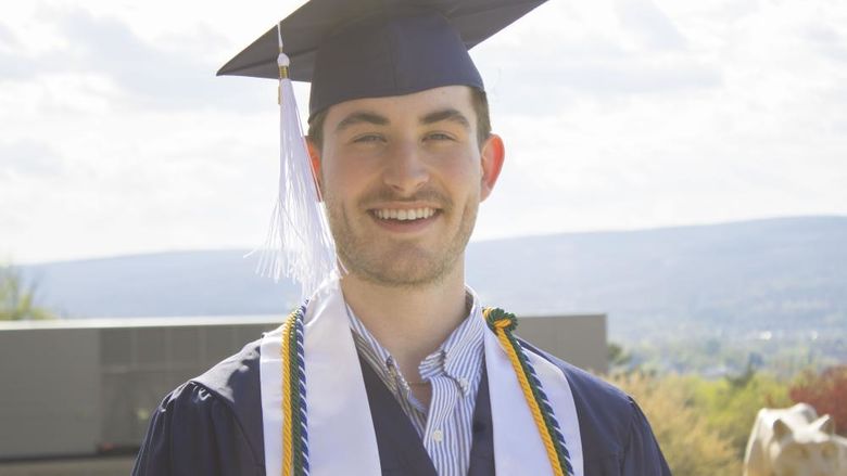 Student wearing commencement regalia and smiling