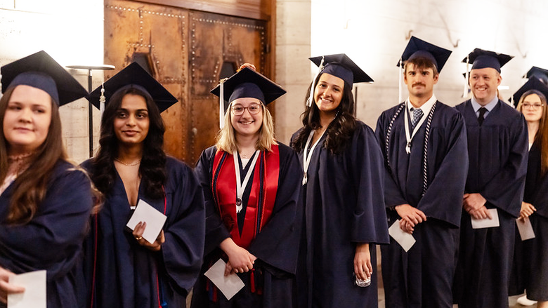 group of grads in cap and gown smiling