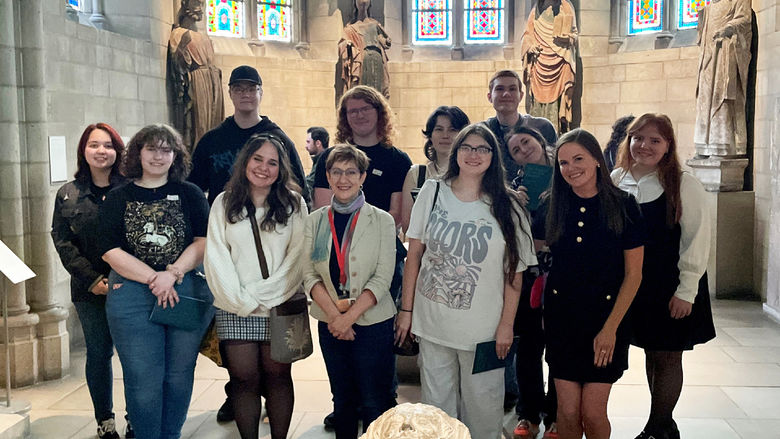 students posing in a two-row, standing formation inside The Cloisters museum