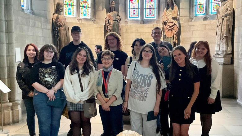 students posing in a two-row, standing formation inside The Cloisters museum