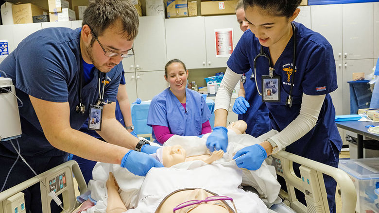 two nursing students practice with mannequin mother and baby