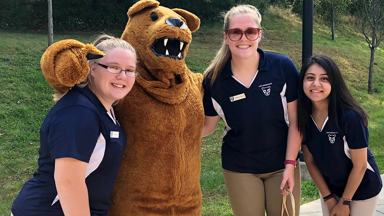 Thre students wearing Penn State shirts pose with the Nittany Lion mascot