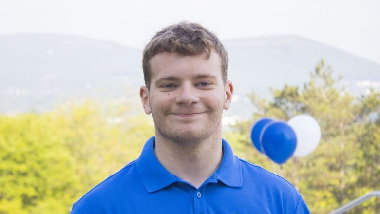 NSO Leader, Paul, smiles with balloons in the background. 