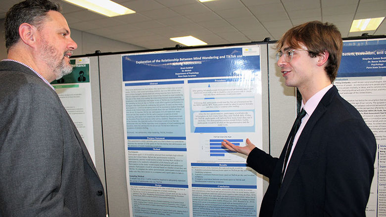 student explains Psychology Poster to teacher at Research Fair