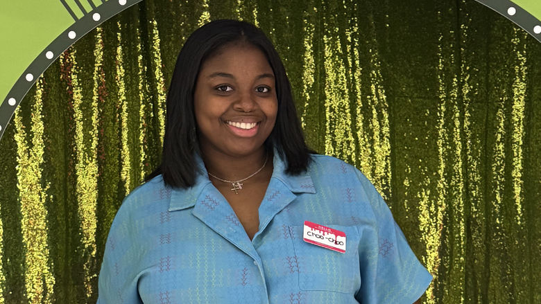 Charrise Lamothe poses for a photo in front of a green curtain