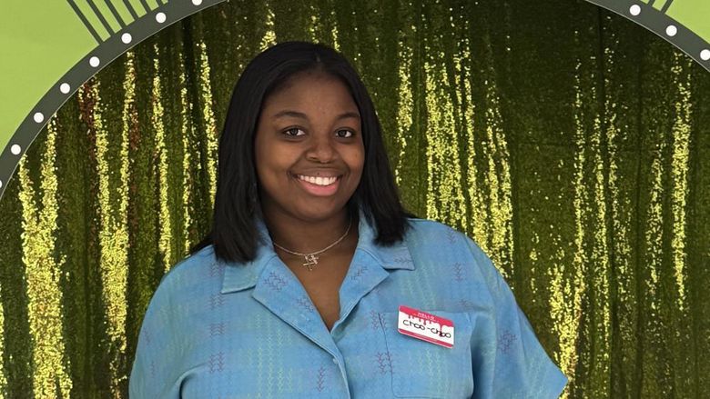 Charrise Lamothe poses for a photo in front of a green curtain