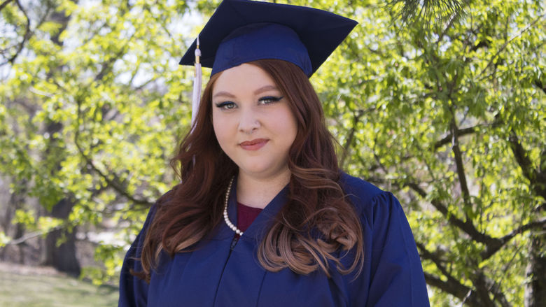 Student wearing commencement regalia and smiling