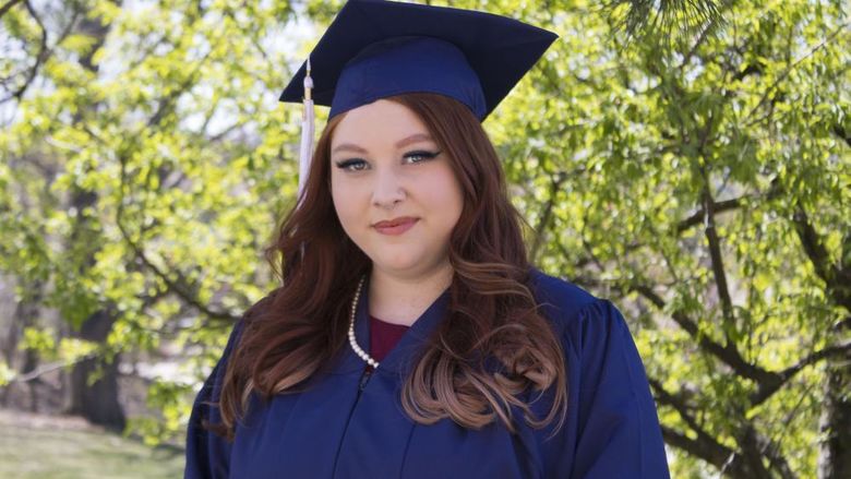 Student wearing commencement regalia and smiling