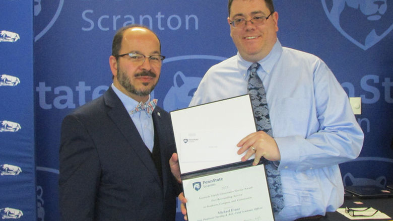 man in suit presents certificate to smiling man