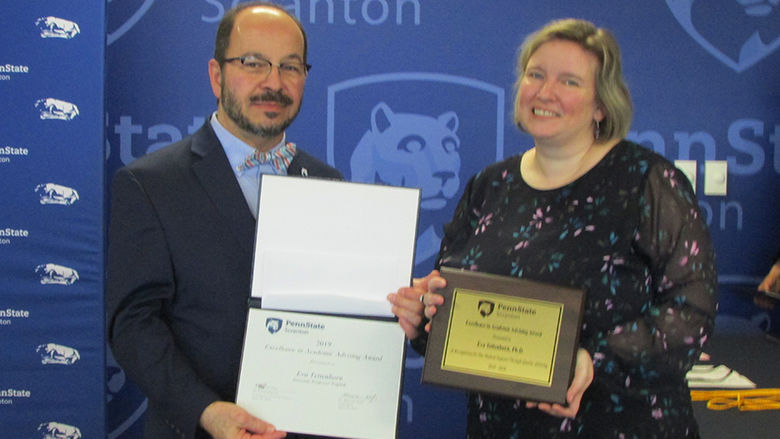 man in suit presents certificate to smiling woman