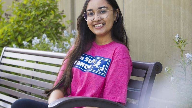 Student sits on bench and smiles