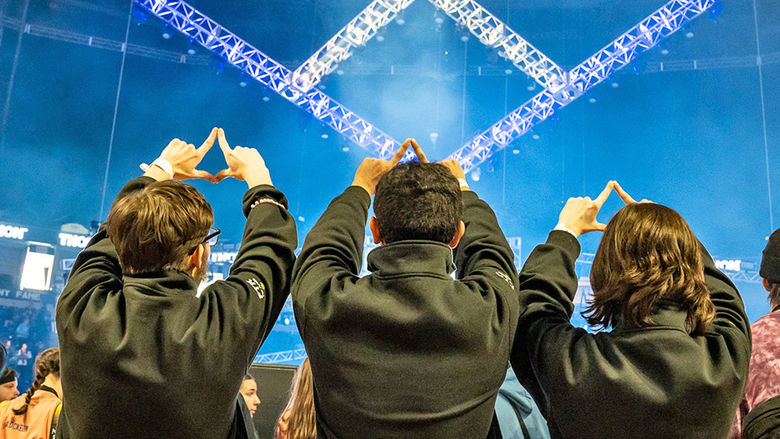 3 students make shape of diamond with fingers in the air