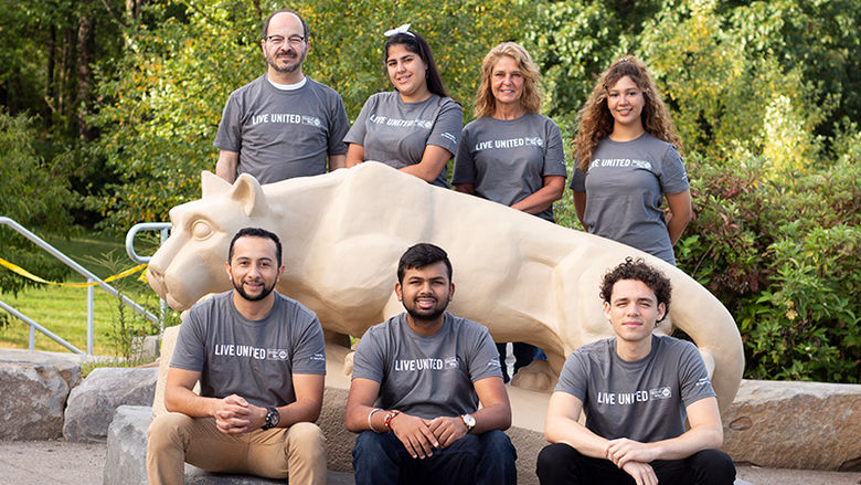 seven people with wearing Live United tee shorts pose near Lion Shrine statue on Scranton's campus