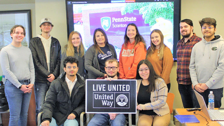 Group of casually dressed student volunteers pose for a photo at a table