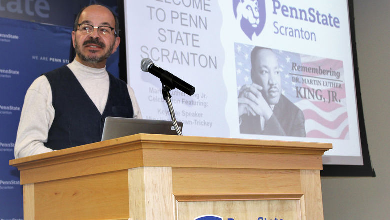 Chancellor Marwan Wafa speaking at podium with MLK Jr image on screen behind him