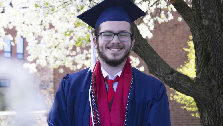 Student wearing commencement regalia and smiling