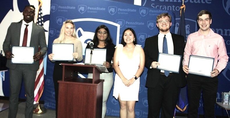a group of students show off their award certificates onstage at the annual dinner event