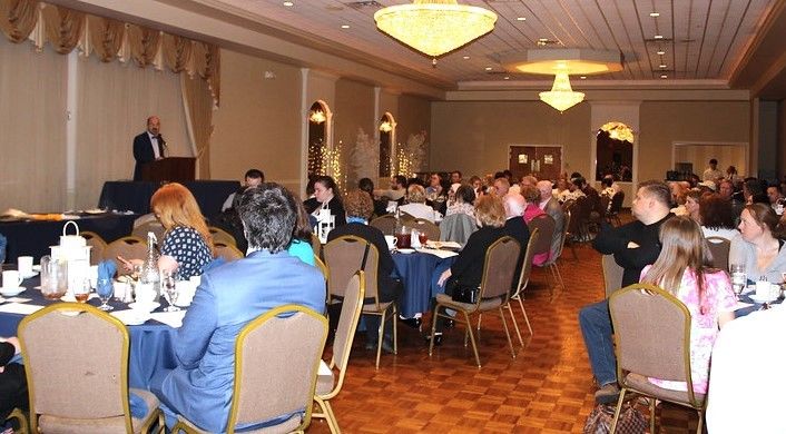 Chanceller wafa stands at podium and addresses the seated crowd at annual awards dinner